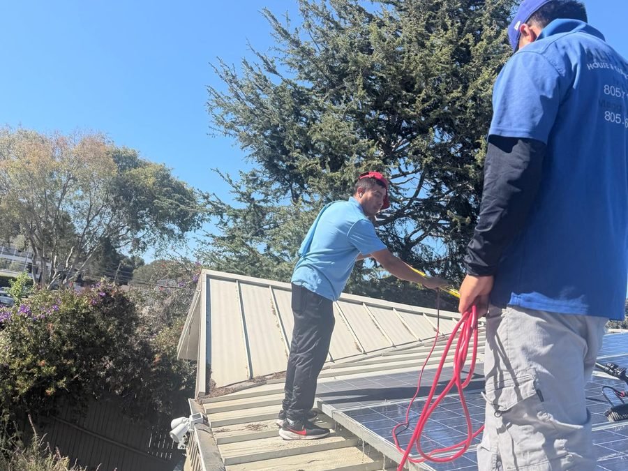 Technician cleaning rooftop solar panels with a water-fed pole (900×700)